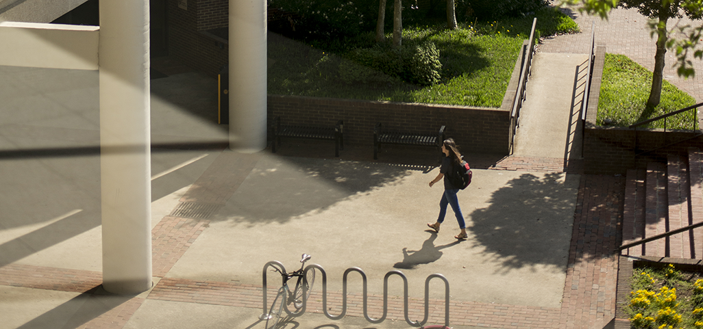 A young woman walks toward the entrance to Oliver Hall.